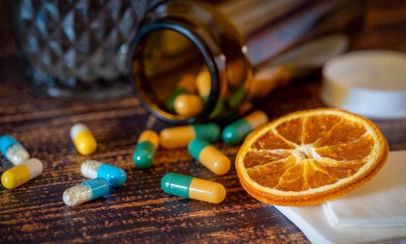 Close-up of vitamins, pills, and dried orange slice for cold relief.