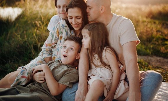 A joyful family enjoying quality time together on a sunset-lit meadow.